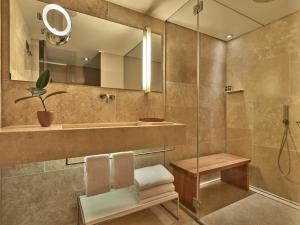 a bathroom with a shower and a chair and a sink at Conservatorium Hotel in Amsterdam