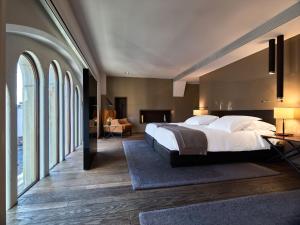 a bedroom with a large bed and large windows at Conservatorium Hotel in Amsterdam