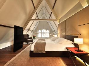 a bedroom with a large bed and a chair at Conservatorium Hotel in Amsterdam