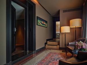 a living room with a chair and a table and a mirror at Conservatorium Hotel in Amsterdam