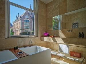 a bathroom with a tub and a window and a sink at Conservatorium Hotel in Amsterdam