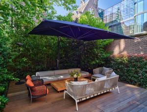 a patio with a couch and a table with an umbrella at Conservatorium Hotel in Amsterdam
