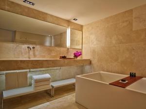 a bathroom with a tub and a sink and a mirror at Conservatorium Hotel in Amsterdam
