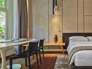 a bedroom with a bed and a table and chairs at Conservatorium Hotel in Amsterdam