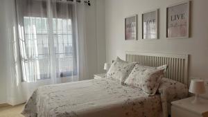 a white bedroom with a bed and two windows at La Tahona in Nerja