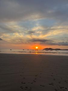 a sunset on a beach with footprints in the sand at Casa Nocodesa in Nicoya
