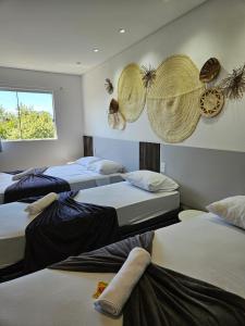 a room with three beds with hats on the wall at Pousada Coração do Rosa - com Piscina Jacuzzi charme e conforto Pertinho do centrinho do Rosa in Praia do Rosa +172 photos