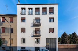 un alto edificio bianco con balconi e auto parcheggiate di fronte di Smile Suite in Milan a Milano