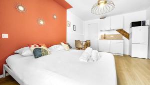 a large white bed in a room with an orange wall at Studio cosy tout équipé proche de Genève in Viry