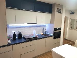 a kitchen with white cabinets and a black counter top at Serana Home in Cisnădie