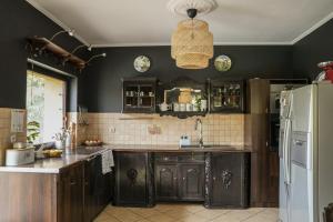 a kitchen with black cabinets and a white refrigerator at Relaks w boberkach Prywatna sala do Bilarda in Bobrowiec