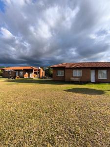a house with a grass field in front of it at Hotel Aimara in Mina Clavero