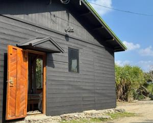 una casa negra con una puerta abierta y una ventana en Wataren Campsite - Vacation STAY 90228v, en Yasukiyaba