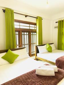 two beds in a room with green curtains at Ceyonra Evermist Residence in Nuwara Eliya