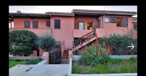una casa rosa con una escalera delante en Appartamento LUCAS, en Stintino