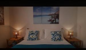 Un dormitorio con una cama con dos lámparas y un cuadro. en Appartamento LUCAS, en Stintino