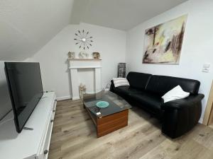 a living room with a black couch and a tv at Friedrich Neunzehn in Andernach