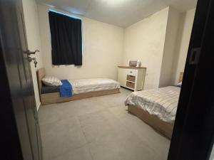 a small bedroom with two beds and a window at Къща за гости при ЮКАТА in Veliko Tŭrnovo