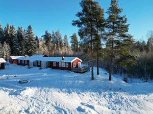 a red cabin in the snow with snow covered ground at Wildlandia Älg Ferienhaus in Hagfors