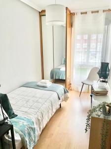 a bedroom with a bed and a chair and a window at Apartamento San Lázaro. in Oviedo