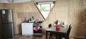 a kitchen with a stove and a table and a refrigerator at Domos Nahuelbuta in Angol
