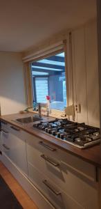 a kitchen with a stove and a sink and a window at Chalet J151 in Heel