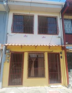 a yellow and white building with barred windows at Playa sol y arena in Puntarenas