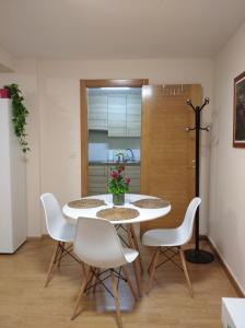 a dining room with a table and white chairs at Castelao Apartments in Arzúa