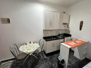 a small kitchen with a table and chairs and a counter at Loft microcasa em Altos da Cidade - perto de tudo in Bauru