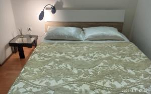 a bed in a bedroom with a lamp and a table at Apartman Oaza Olja in Belgrade