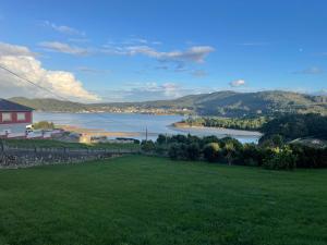 a green field with a view of a river at Lar Etxea O Barqueiro in O Barqueiro +13 photos