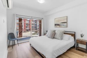 a white bedroom with a bed and a window at Luxury Lake View Condo in West Kelowna, 5 Star Resort with Pool, Hot Tub and Gym in West Kelowna