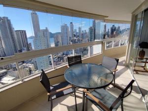 un tavolo e sedie su un balcone con vista sulla città di Encanto nas Alturas: Acomode-se no Elegante Edifício Arnoldo Werner em Balneário Camboriú a Balneário Camboriú