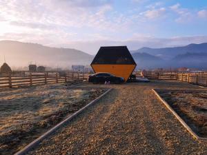 a small house sitting on the side of a field at Vulyk Guesthouse in Verkhovyna