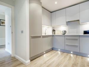 une cuisine avec des armoires blanches et un plancher en bois dans l'établissement Beautiful City Centre Apartment, à Belfast 12 autres photos