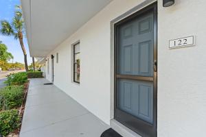 a blue door on a white building with a sidewalk at Exquisite Luxury First Floor Condo - Easy Walk to Amenities in Naples
