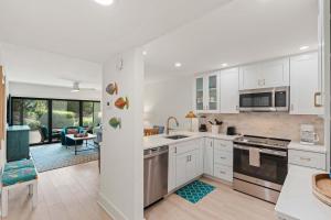 a kitchen with white cabinets and a living room at Exquisite Luxury First Floor Condo - Easy Walk to Amenities in Naples +41 photos