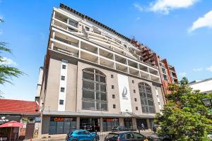 Un edificio alto y blanco con coches aparcados delante. en Self-Check-In, Restaurants, Cafe's, Pubs, Work or Vacay, en Ciudad del Cabo