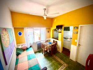 a room with yellow walls and a kitchen with a table at La Vecindad del Sol Depto G in Miramar