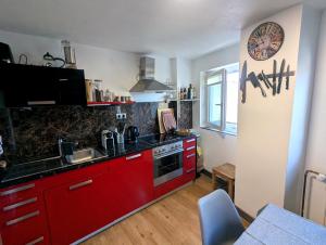 a kitchen with red cabinets and a clock on the wall at Rooftop-Apartment Citylage in Offenburg