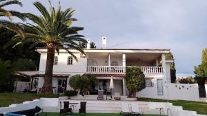 a white house with a palm tree and chairs at Villa Tranquilla in Estepona