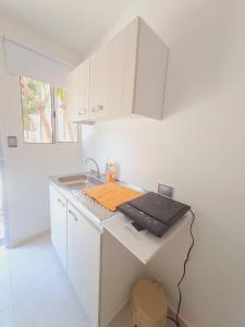 une cuisine blanche avec un évier et un comptoir dans l'établissement Apartaestudio completo cerca Barranquilla, à Galapa 3 autres photos