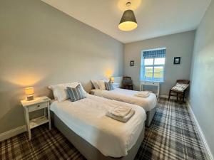 two beds in a room with two tables and a window at Lagoon View - Sea View- Pet Friendly - 2 Bed Apt - En-suite in Trearddur