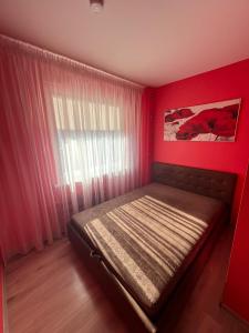 a bedroom with a bed in a red room with a window at LuXury Apartment on Naujakiemis Street in Klaipėda