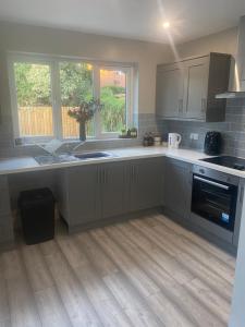 a kitchen with white cabinets and a wooden floor at Station Road 3 bed semi detached in Belfast