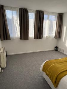 a bedroom with a bed and two windows at Beautiful-2 bedroom Apartment, 1 bathroom, sleeps 6, in greater london (South Croydon). Provides accommodation with WiFi, 3 minutes Walk from Purley Oak Station and 10mins drive to East Croydon Station in Purley