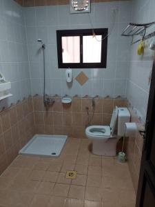 een badkamer met een toilet, een raam en een bad bij Pool House at Janabiyah in Al Janabīyah +13 foto's