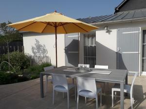 a table and chairs with an umbrella on a patio at Maison à Lancieux de plain pieds avec cour fermée in Lancieux