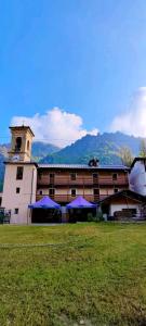 a building with a clock tower and a building with purple umbrellas at CASA ALPINA Don Fisanotti - Piazzette - Usseglio in Usseglio