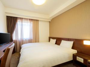 a hotel room with a bed and a window at Dormy Inn Takamatsu in Takamatsu
